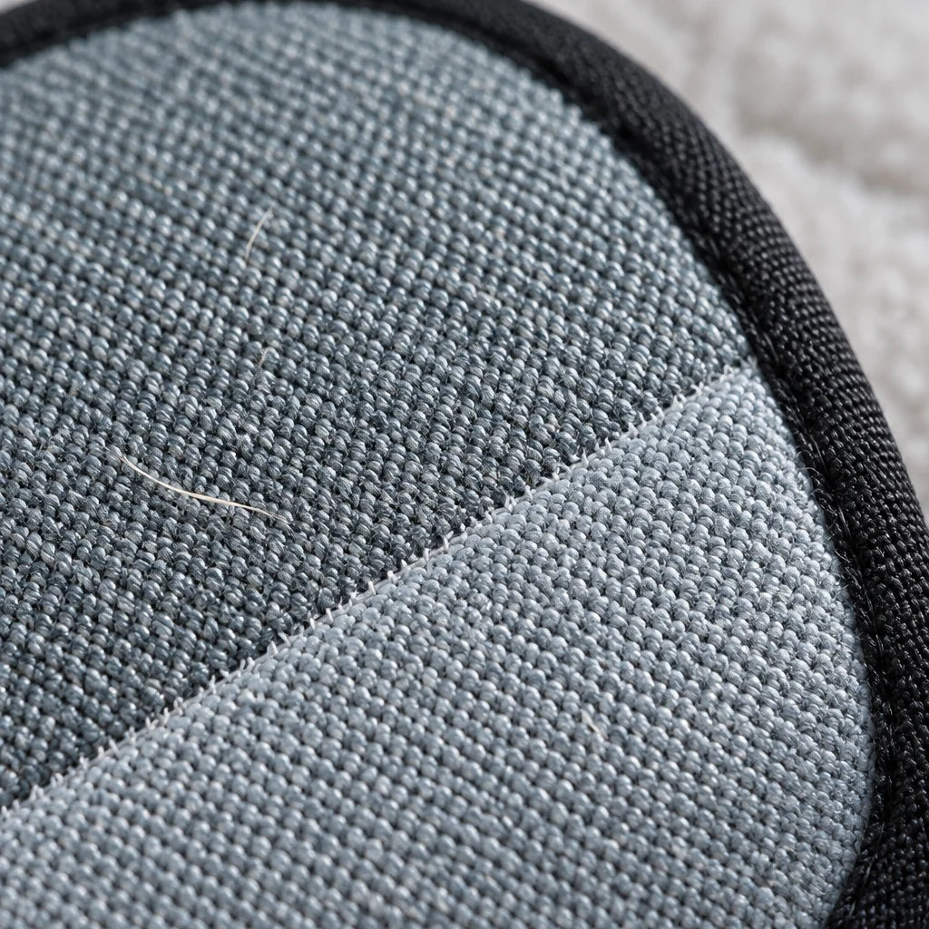 A square macro photograph of the exact brush’s grey textile face, its fine diagonal woven fibers and