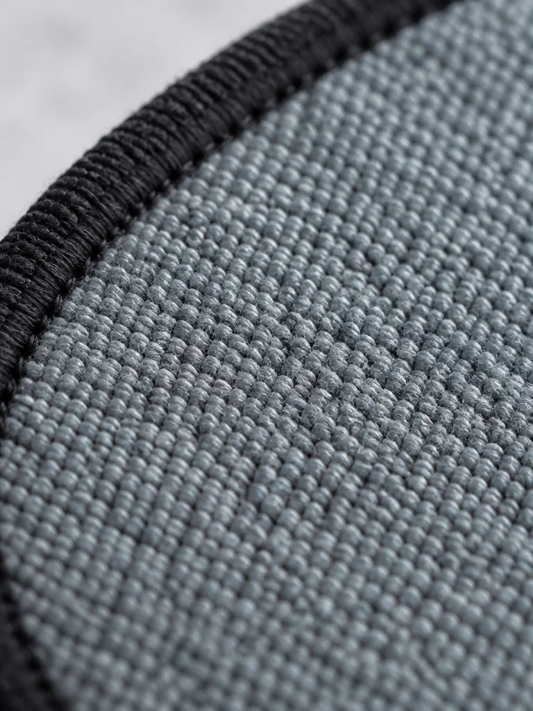 A portrait macro photograph of the exact brush’s grey textile face at very close range: densely wove